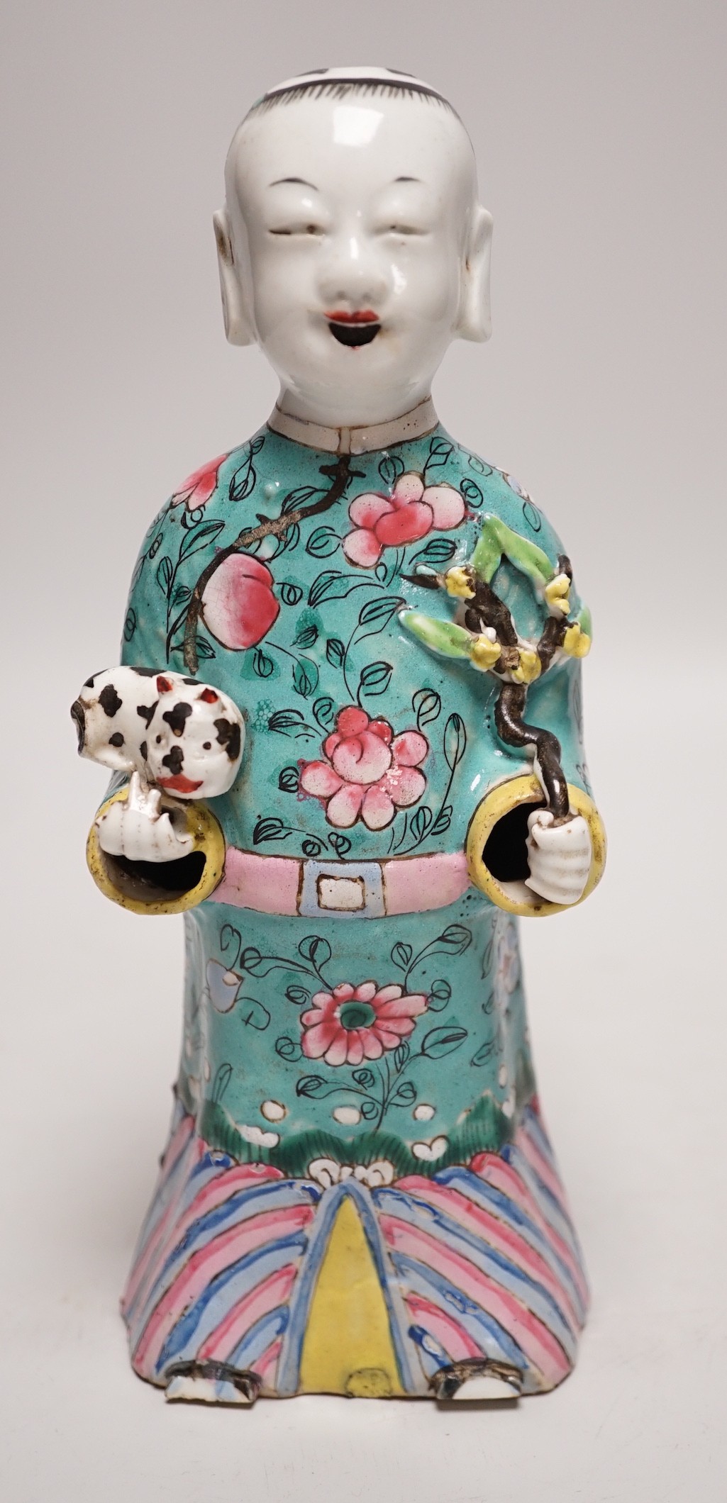 An early 19th century Chinese enamelled porcelain figure of a boy holding a cat and a sprig of prunus, 20cm